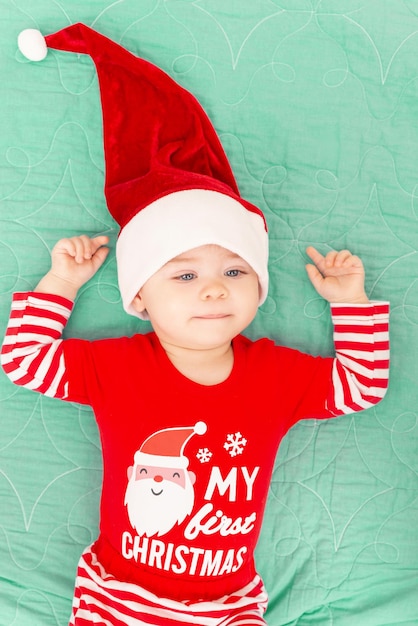 Cute Little Baby Boy con gorro de Papá Noel en su primer niño adorable de Navidad acostado en verde