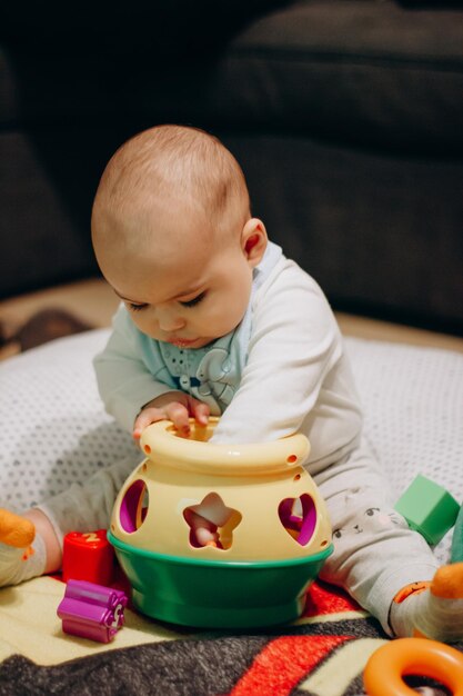 Cute Little Baby Boy jugando al juguete clasificador sentados en el suelo en casa