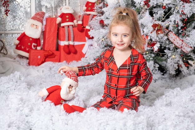 Cute Little Baby Girl jugando con el juguete de santa claus en la habitación decorada de Navidad