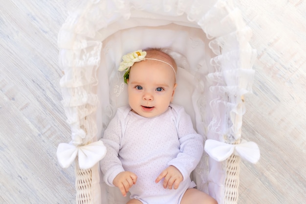 Cute Little Baby Girl en un traje blanco se encuentra en una hermosa cuna de cuna