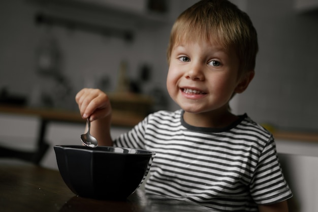 Cute little boy comiendo avena para el desayuno.