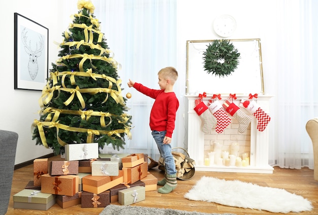 Cute little boy decorar el árbol de Navidad en casa