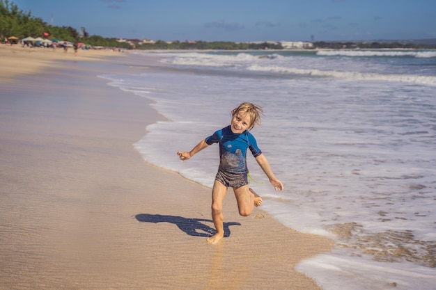 Cute little boy divirtiéndose en la playa tropical durante las vacaciones de verano