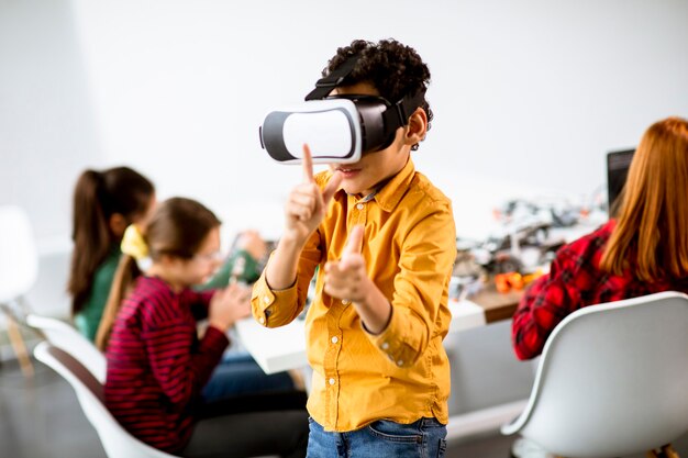 Cute little boy con gafas de realidad virtual VR en un aula de robótica