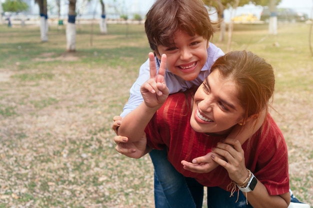 Cute little boy jugando con su madre durante un paseo por el parque