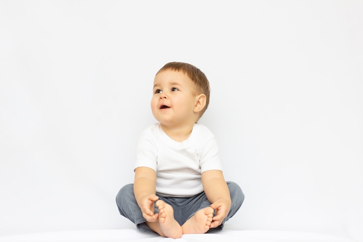 Foto cute little boy sentado aislado sobre fondo blanco. buscando concepto.