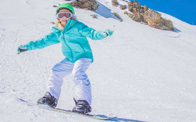 Cute Little Girl Snowboard en la estación de esquí en un día soleado de invierno.