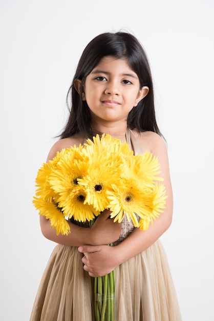 Cute Little Indian Girl sosteniendo un ramo o ramo de flores frescas de Gerbera amarilla. Aislado sobre fondo blanco