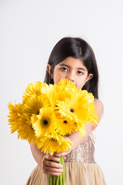 Cute Little Indian Girl sosteniendo un ramo o ramo de flores frescas de Gerbera amarilla. Aislado sobre fondo blanco