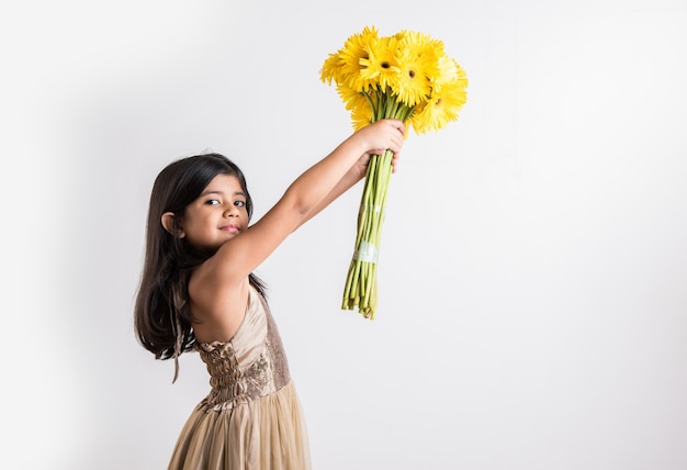 Cute Little Indian Girl sosteniendo un ramo o ramo de flores frescas de Gerbera amarilla. Aislado sobre fondo blanco
