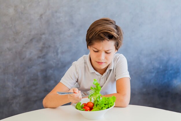 Cute, menino adolescente, comendo salada