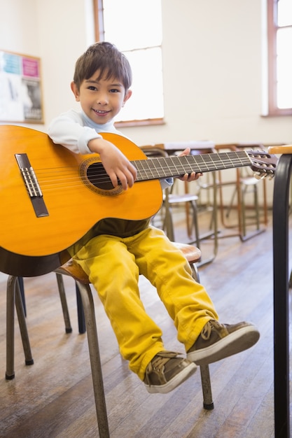 Foto cute pupila tocando violão na sala de aula