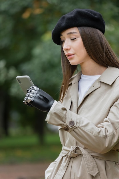 Cyber mujer en un impermeable con una prótesis biónica en el brazo está hablando por teléfono con amigos