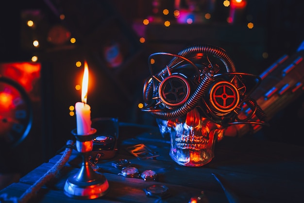 Cyberpunk-Atmosphäre. Totenkopf in Steampunk-Brille auf einem Tisch mit Mechanismen mit neonfarbenem Licht