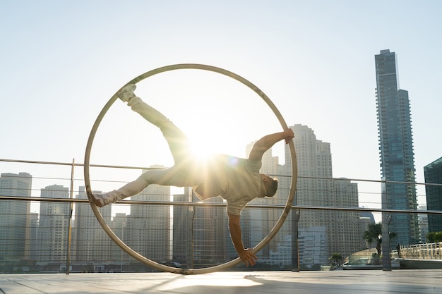 Cyr Wheel-Künstler mit Stadtbildhintergrund von Dubai während des Sonnenuntergangs.