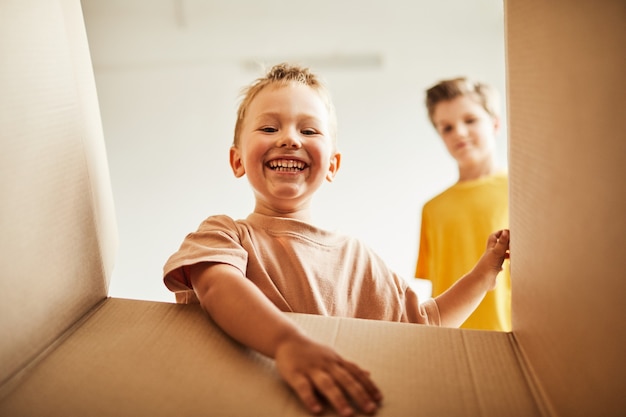 Da foto de caixa de dois meninos desfazendo as malas enquanto a família se muda para uma nova casa, copie o espaço