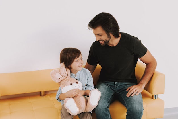 Dad comforts kid na sala de espera da clínica pediátrica