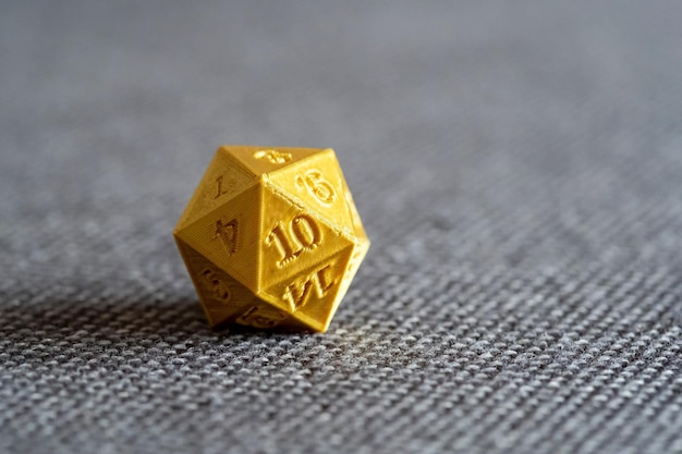 Foto dados de jogo de rpg d20 impressos em 3d em ouro em uma cama objeto macro detalhe estreito closeup ninguém jogando rpg de mesa jogos de tabuleiro larp e acessórios de impressão 3d geek nerd símbolo de cultura conceito abstrato