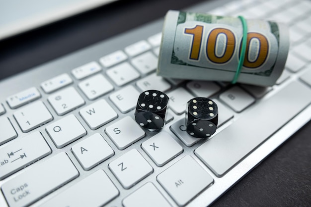 Dados e notas de dólar em um novo teclado de laptop isolado em uma mesa preta Casino online e cubos de conceito de jogo para jogos