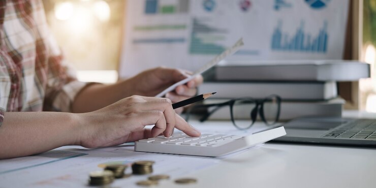Dados financeiros analisando a escrita à mão e contando com a calculadora no escritório na mesa de madeira