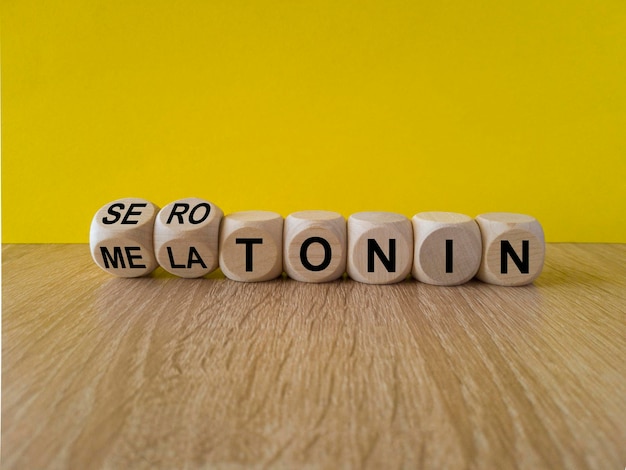 Los dados forman las palabras serotonina y melatonina. Hermoso fondo amarillo mesa de madera Copiar espacio