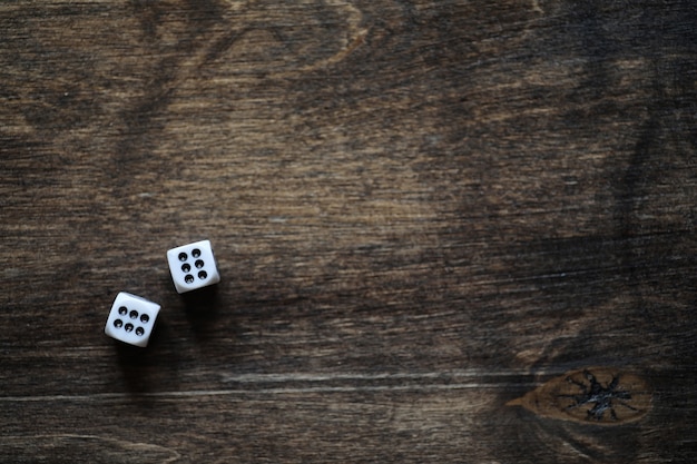 Dados pequenos brancos em uma mesa de textura de madeira marrom