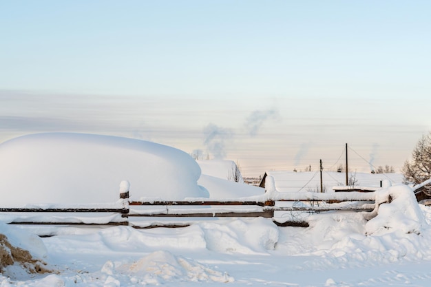 Dächer von kleinen Häusern mit Schnee bedeckt mit Rauch aus Schornsteinen an sehr kalten Wintertagen