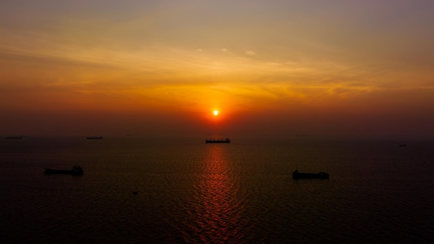 Dämmerung des Meereslandschafts und Silhouette des Containerschiffs, das im Meer und über dem Sonnenlicht-Hintergrund schwimmt