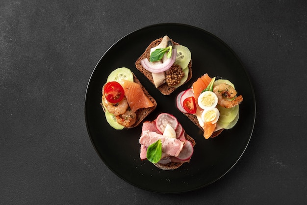 Dänische Sandwiches auf einer schwarzen Platte von oben