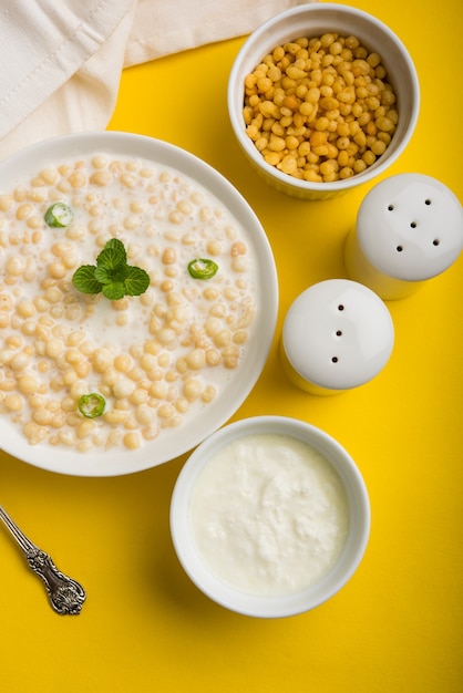 Dahi Bundi oder Boondi Raita mit Quark, ist eine beliebte Beilage aus Rajasthan, Indien. Serviert mit Koriander-Toppings in einer Schüssel auf buntem oder hölzernem Hintergrund. Selektiver Fokus