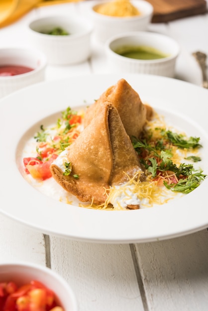 Foto dahi samosa o samosa es un bocadillo popular del norte de la india bañado en cuajada, comida chatarra favorita a la hora del té servida con tamarindo y salsa picante de menta o salsa de tomate y chile verde frito.