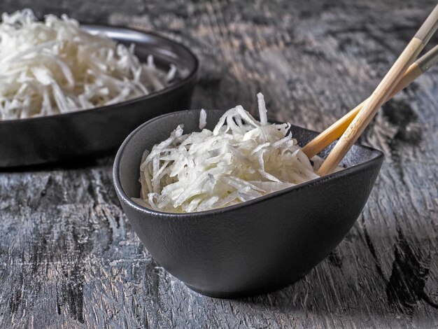 Daikon ralado em pratos de cerâmica preta com close-up de pauzinhos