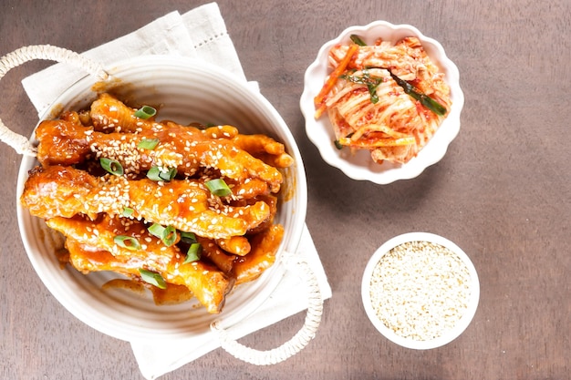 Dakbal o Maeun Dakbal son patas de pollo picantes, estilo de comida coreana servida con semillas de sésamo y kimchi.