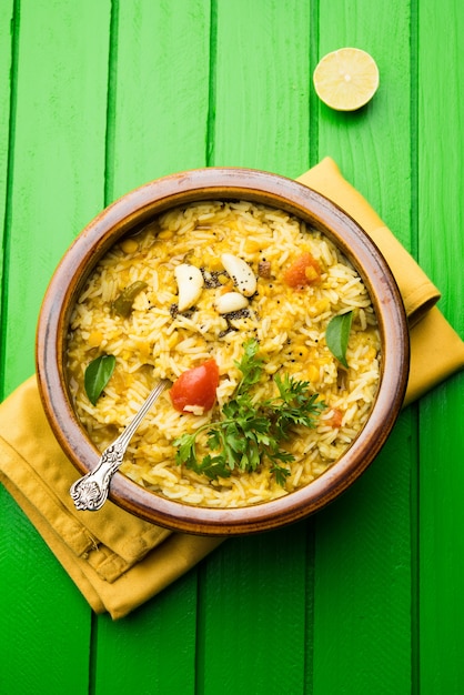 Foto dal khichadi o khichdi sabrosa receta india servida en un tazón sobre un fondo de mal humor está hecha de toovar dal y arroz combinado con especias enteras, cebollas, ajo y tomates, etc. enfoque selectivo