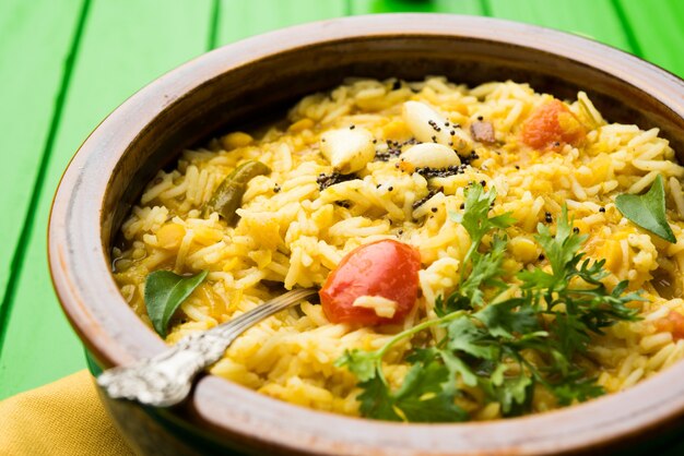 Foto dal khichadi ou khichdi tasty receita indiana servida em uma tigela sobre um fundo melancólico é feita de toovar dal e arroz combinado com especiarias inteiras, cebola, alho e tomate, etc. foco seletivo