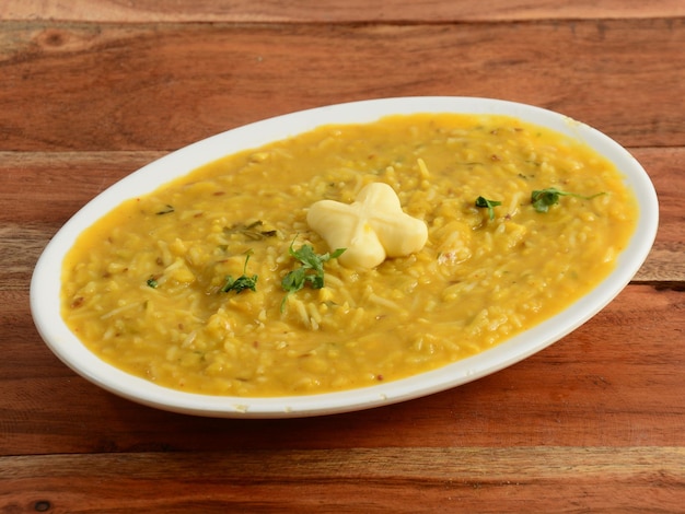 Dal Khichdi oder Khichadi Leckeres indisches Rezept, serviert in einer Schüssel auf rustikalem Holzhintergrund Das Essen aus Dal und Reis kombiniert mit ganzen Gewürzen, Zwiebeln, Knoblauch und Tomaten usw. Selektiver Fokus