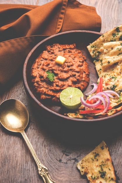 Dal Makhani oder Daal Makhni ist ein beliebtes Essen aus Punjab, Indien, das aus ganzen schwarzen Linsen, roten Kidneybohnen, Butter und Sahne hergestellt und mit Knoblauch-Naan oder indischem Brot oder Roti . serviert wird