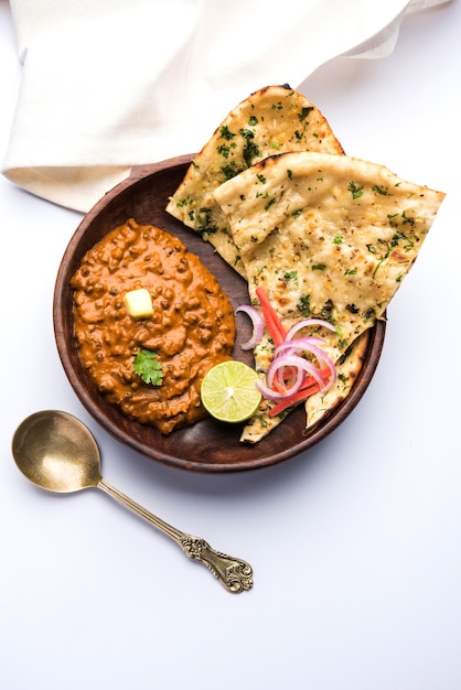 Dal Makhani oder Daal Makhni ist ein beliebtes Essen aus Punjab, Indien, das aus ganzen schwarzen Linsen, roten Kidneybohnen, Butter und Sahne hergestellt und mit Knoblauch-Naan oder indischem Brot oder Roti . serviert wird