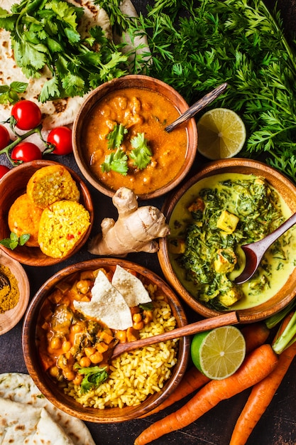 Foto dal, palak paneer, curry, arroz, chapati, chutney en cuencos de madera en la mesa oscura.