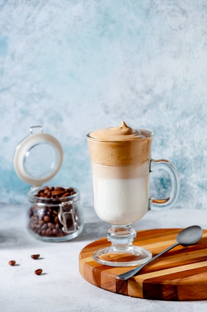 Foto dalgona café na superfície da luz. café chicoteado cremoso na moda. bebida fria de verão coreana