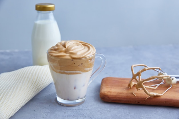 Dalgona-Kaffee auf grauem Hintergrund. Modisches Getränk mit flauschiger Creme auf Basis von Milch, Kaffee und Zucker.