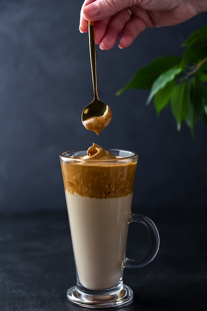 Dalgona Kaffee machen. Hand mit einem Löffel Schlagsahne