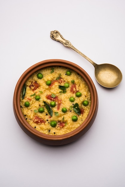 Dalia o Daliya Khichadi de verduras o Khichdi de trigo roto con tomate, guisantes y guindilla, servido en un tazón o plato