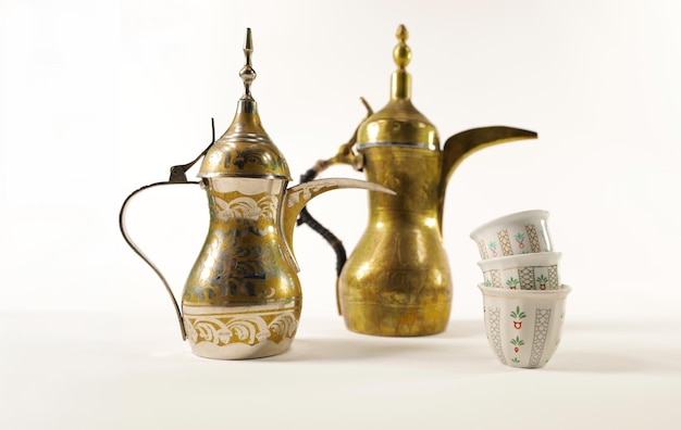 Dallah árabe tradicional antiguo con tazas en fondo blanco generalmente servido en días festivos como Eid