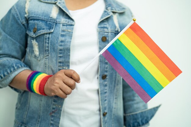 Una dama asiática con pulseras con la bandera del arco iris y sostiene el símbolo del corazón rojo del mes del orgullo LGBT celebra anualmente en junio la actividad social de los derechos humanos de las personas gay, lesbianas, bisexuales y transgénero.