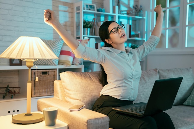 dama asiática con ropa formal extendiendo los brazos y respirando aliviada porque finalmente completó su trabajo. el retrato de una mujer china que trabaja horas extra está haciendo un sonido mientras se estira