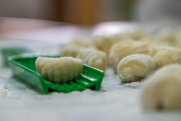 Una dama cocinando ñoquis caseros para el almuerzo La herramienta verde para hacer entonces está en primer plano