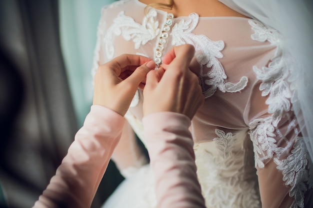 Dama de honra faz nó na parte de trás do vestido de noiva