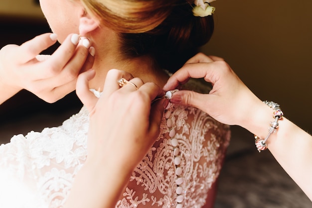 Dama de honra que ajuda a noiva a prender o vestido de casamento