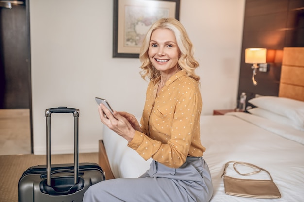 Dama. Elegante mujer rubia en pantalón gris en una habitación de hotel